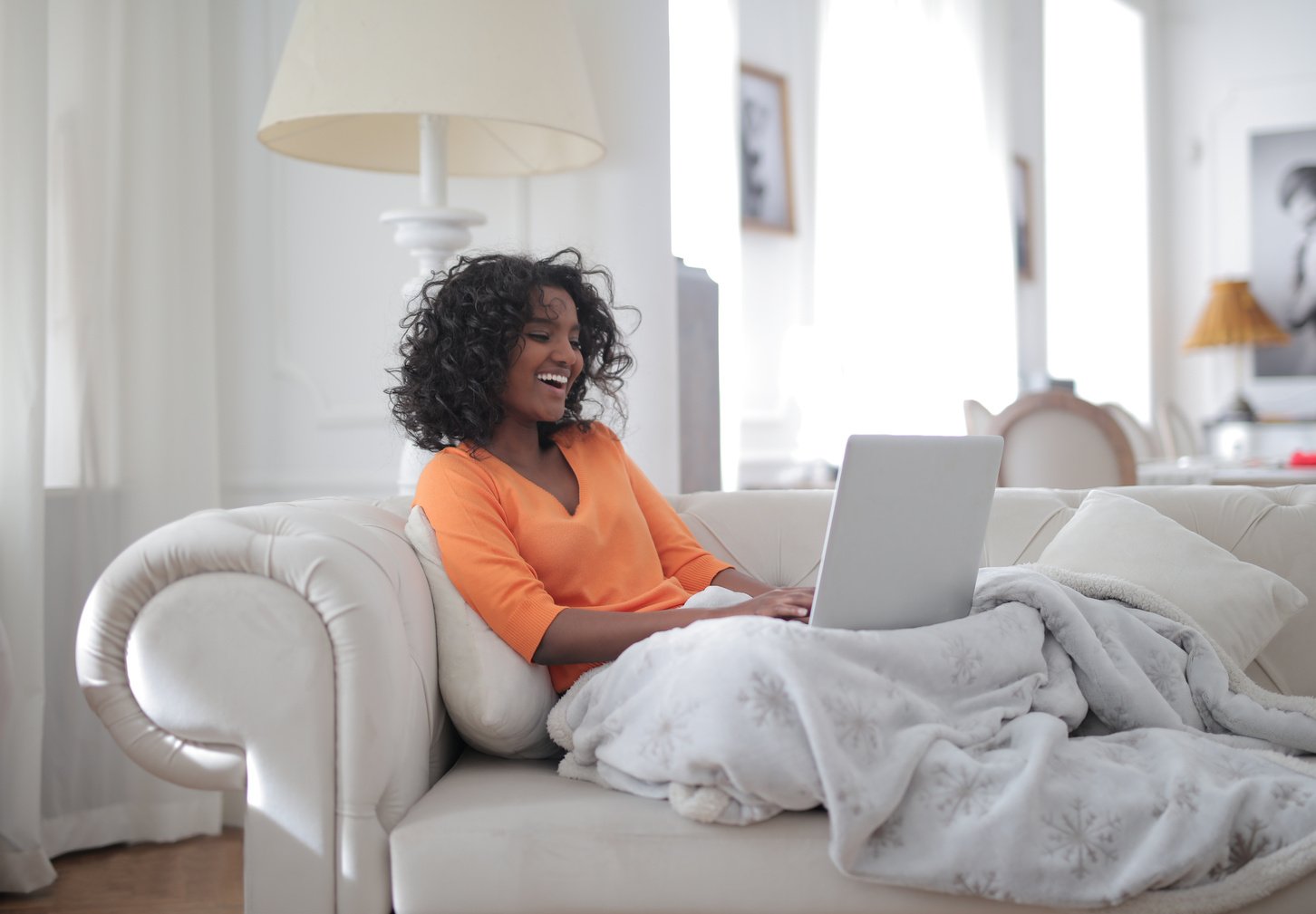 Happy woman using laptop on sofa
